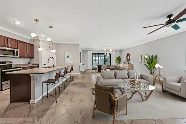 a kitchen with stainless steel appliances granite countertop a sink a stove a refrigerator cabinets and chairs