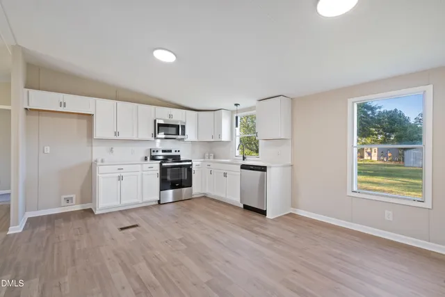 a kitchen with white cabinets and window