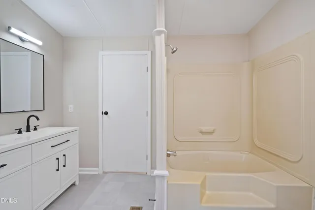 a bathroom with a tub sink and mirror