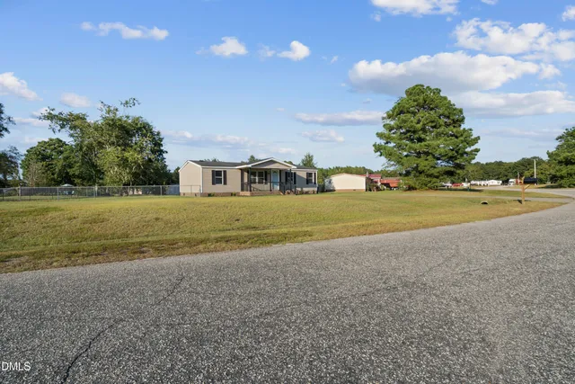 a view of a house with a yard and a large tree