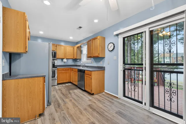 a kitchen with stainless steel appliances granite countertop a refrigerator a sink a stove and a wooden floors