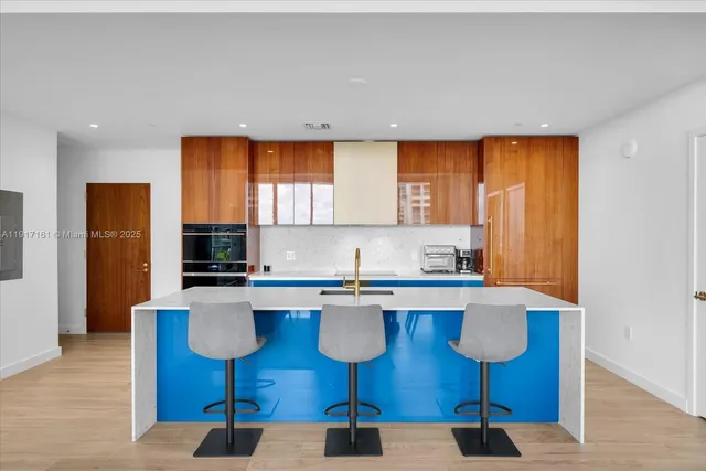 a kitchen with stainless steel appliances a sink a stove a refrigerator cabinets and wooden floor