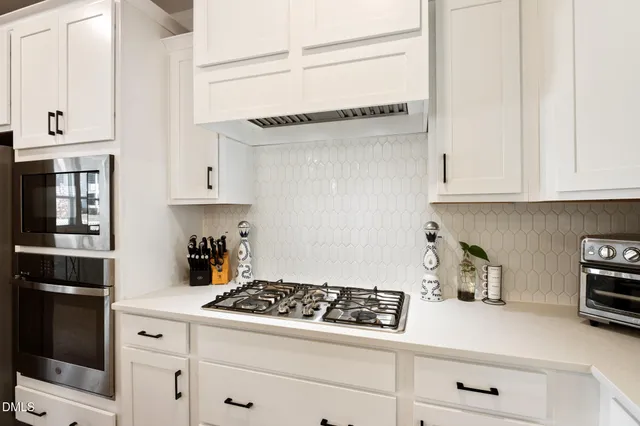 a kitchen with white cabinets and appliances