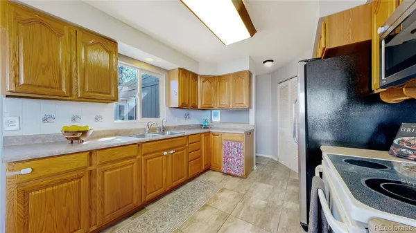 a kitchen with stainless steel appliances granite countertop a sink dishwasher stove and refrigerator with wooden cabinets
