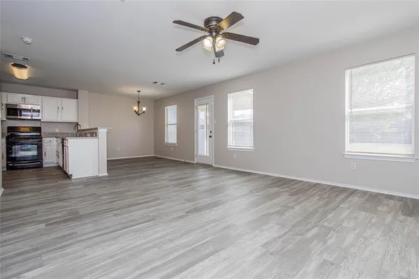 a view of a kitchen with a stove cabinets wooden floor and a ceiling fan