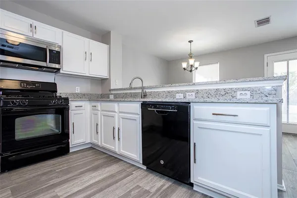 a kitchen with granite countertop a stove top oven a sink and dishwasher with wooden floor