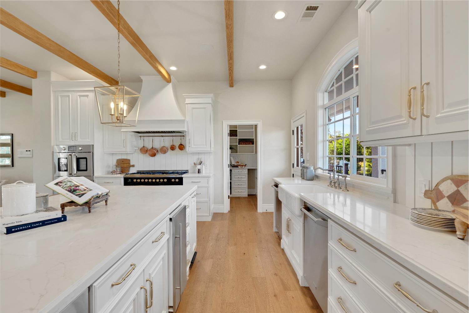 2905 Virginiatown Road Lincoln, CA 95648 - Photo 10 of 86 Kitchen featuring light wood-finish flooring, white cabinetry, a large center island with integrated appliances, and a walk-in pantry