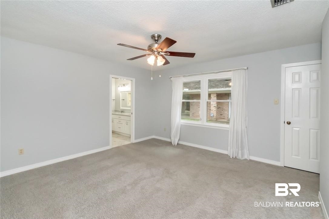 6109 Timberly Road North Mobile, AL 36609 - Photo 16 of 26 Unfurnished bedroom featuring ceiling fan, light colored carpet, ensuite bathroom, and a textured ceiling