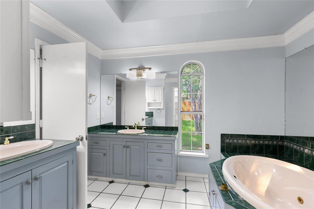 1109 Pine Ridge Drive Azle, TX 76020 - Photo 12 of 24 Bathroom featuring dual vanity sinks with gold-toned faucets, a separate tub, and an arched window providing natural light