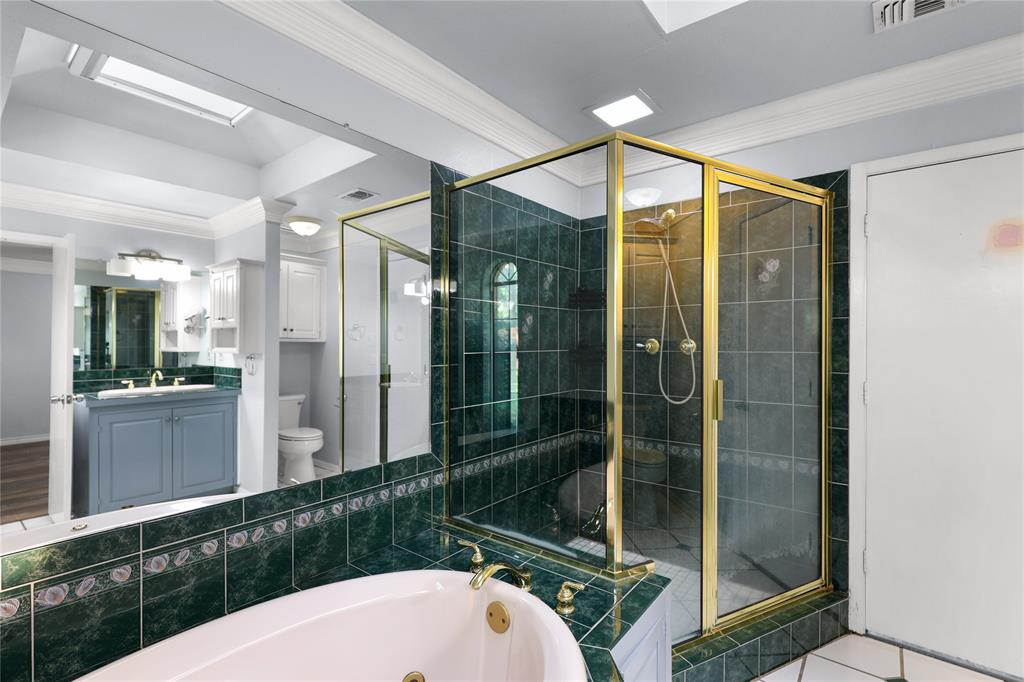 1109 Pine Ridge Drive Azle, TX 76020 - Photo 13 of 24 This bathroom features a spacious soaking tub, a separate shower with a brass-framed glass enclosure, and dark green tiled walls and flooring