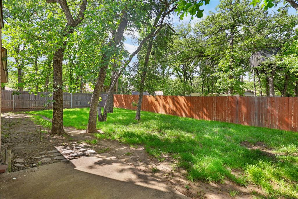 1109 Pine Ridge Drive Azle, TX 76020 - Photo 19 of 24 The property features a fenced yard with mature trees and a lawn area