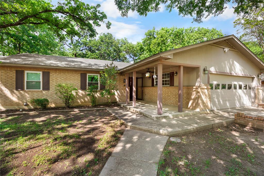 1109 Pine Ridge Drive Azle, TX 76020 - Photo 22 of 24 The property features a brick exterior with a covered front porch, an attached garage, and a concrete pathway leading to the entrance