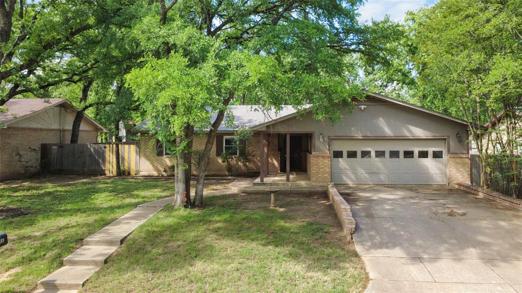 1109 Pine Ridge Drive Azle, TX 76020 - Photo 23 of 24 The property features a front yard with a lawn, mature trees, and a concrete pathway leading to the entrance