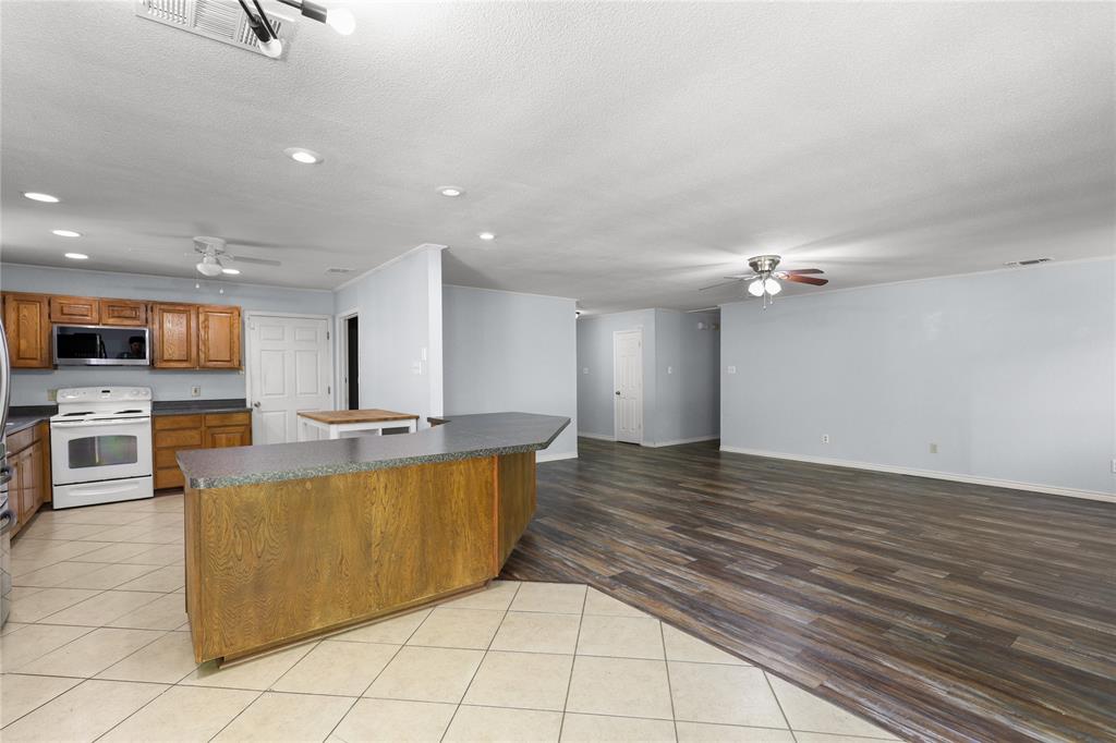 1109 Pine Ridge Drive Azle, TX 76020 - Photo 5 of 24 The property features a kitchen with wood cabinetry, a white range, and a built-in microwave