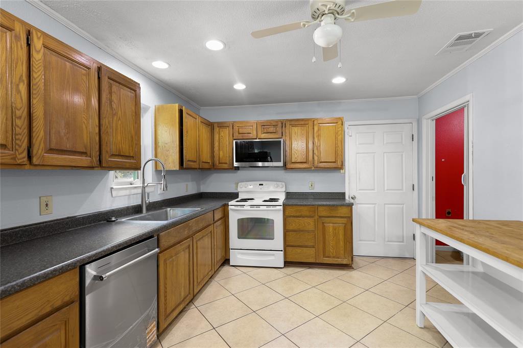 1109 Pine Ridge Drive Azle, TX 76020 - Photo 6 of 24 The kitchen features wooden cabinetry, a stainless steel dishwasher, and a white oven with an overhead microwave