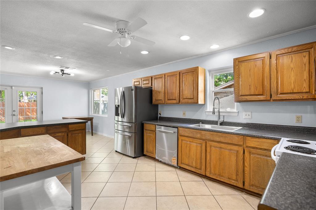 1109 Pine Ridge Drive Azle, TX 76020 - Photo 7 of 24 The kitchen features wooden cabinetry, stainless steel appliances, and a tiled floor