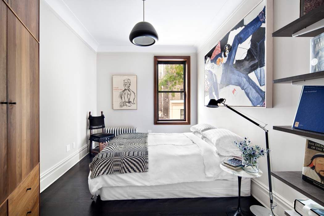 790 Riverside Drive, Unit 1J Manhattan, NY 10032 - Photo 6 of 22 a bedroom with a bed and a chandelier