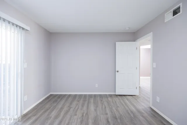 an empty room with wooden floor and window