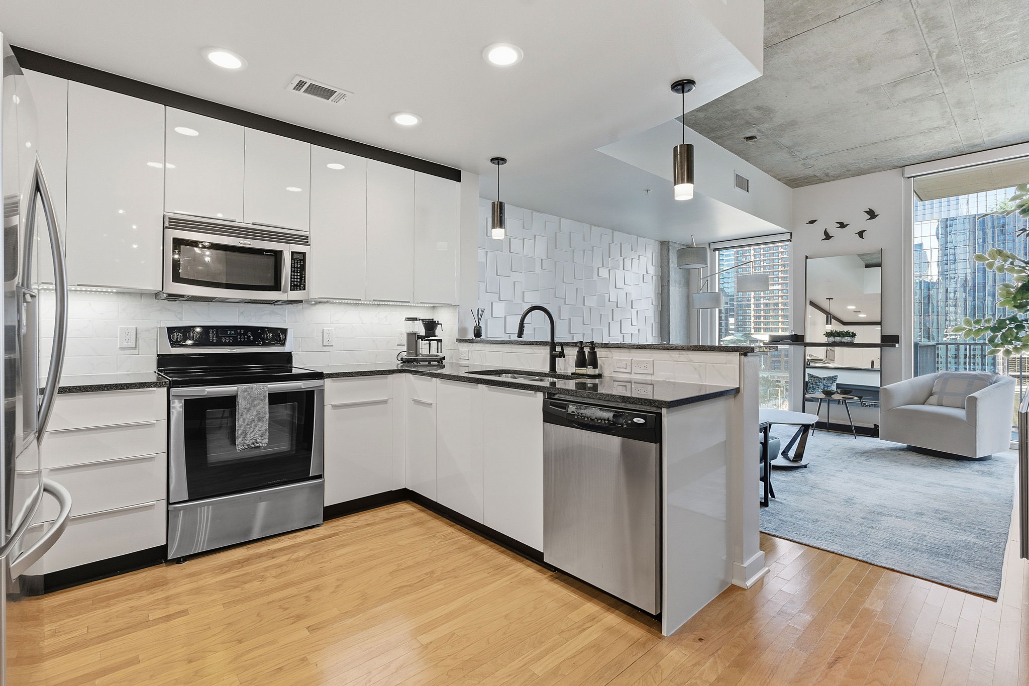 360 Nueces Street, Unit 1007 Austin, TX 78701 - Photo 9 of 40 Kitchen with appliances with stainless steel finishes, a peninsula, pendant lighting, decorative backsplash, and light wood finished floors