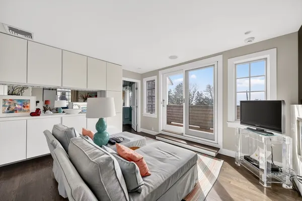 a living room with furniture a flat screen tv and a refrigerator