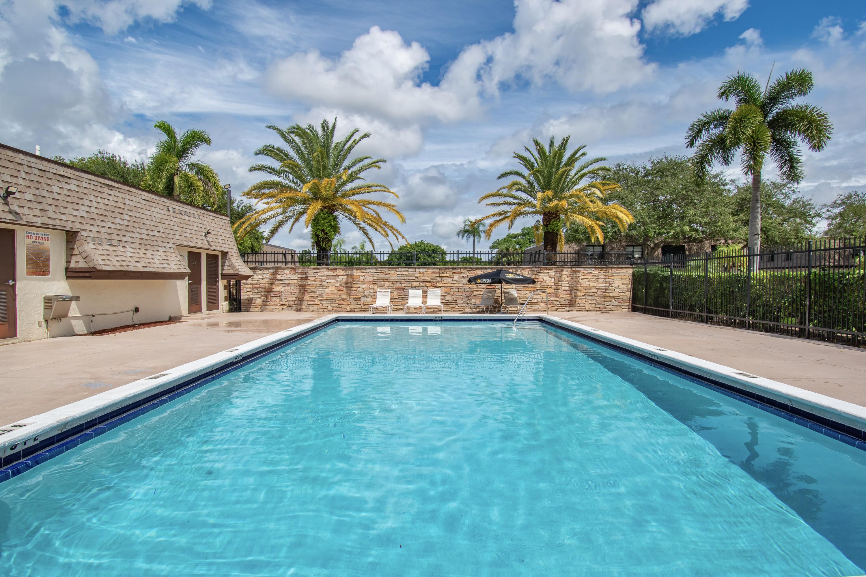 9460 Southwest 61st Way, Unit B Boca Raton, FL 33428 - Photo 28 of 31 a view of a swimming pool with a bench and a palm tree