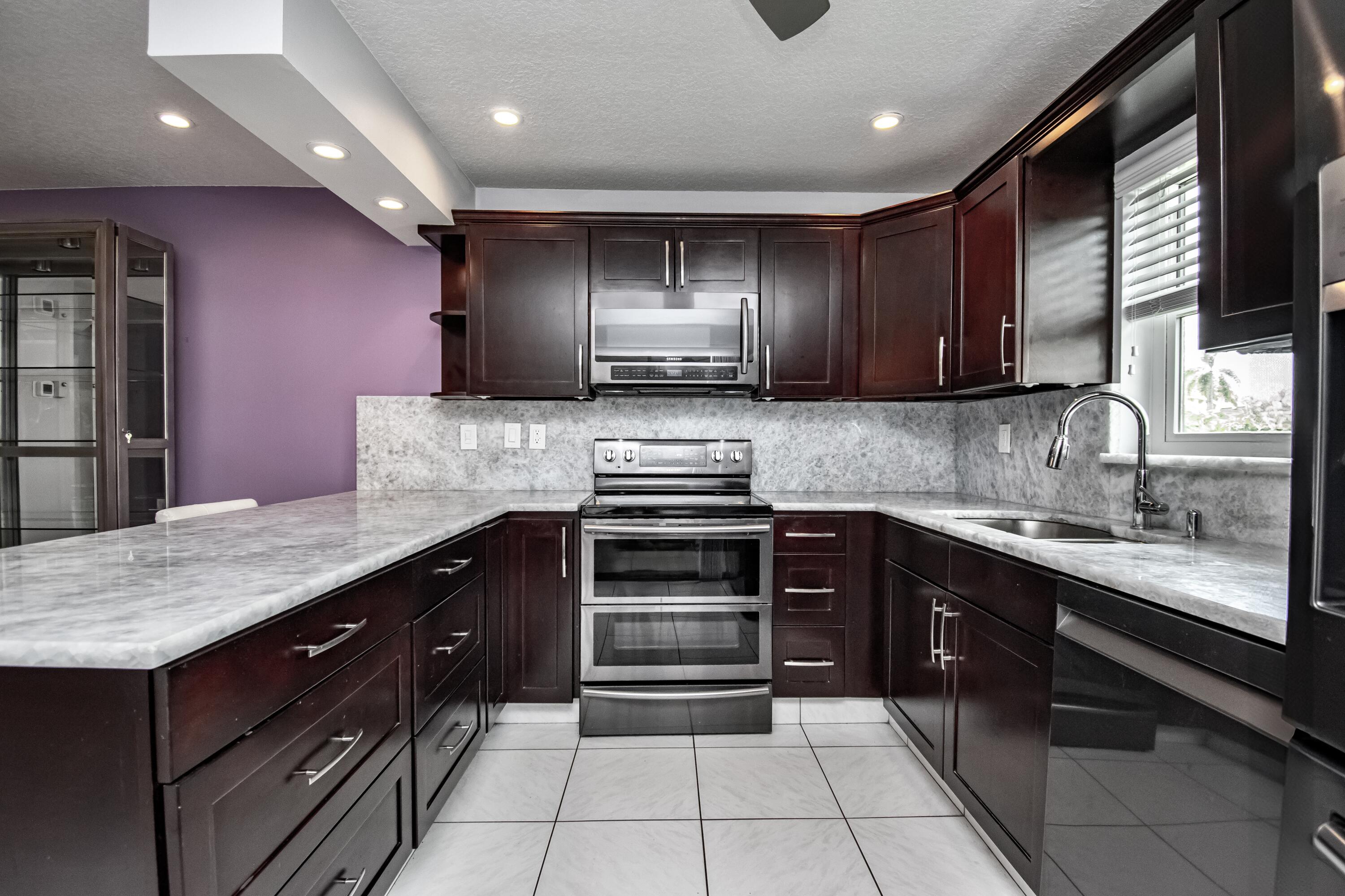 9460 Southwest 61st Way, Unit B Boca Raton, FL 33428 - Photo 6 of 31 a kitchen with kitchen island granite countertop stainless steel appliances and cabinets