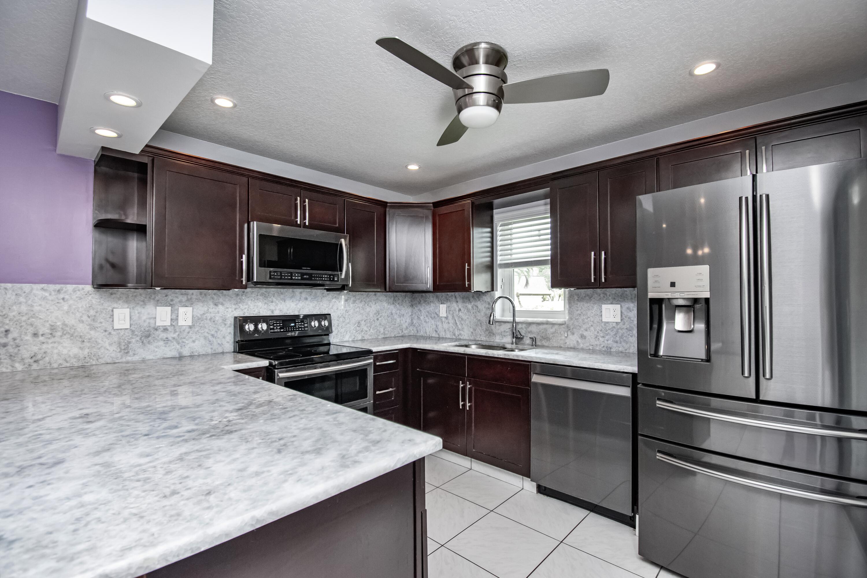 9460 Southwest 61st Way, Unit B Boca Raton, FL 33428 - Photo 7 of 31 a kitchen with stainless steel appliances granite countertop a sink refrigerator and microwave