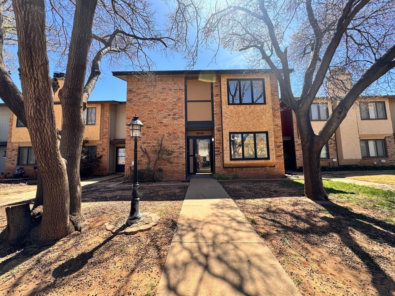 5763 38th Street Lubbock, TX 79407 - Photo 2 of 16 a view of a brick house with a large tree