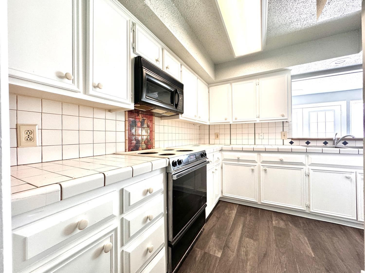 5763 38th Street Lubbock, TX 79407 - Photo 5 of 16 a kitchen with stainless steel appliances granite countertop white cabinets a sink and a oven