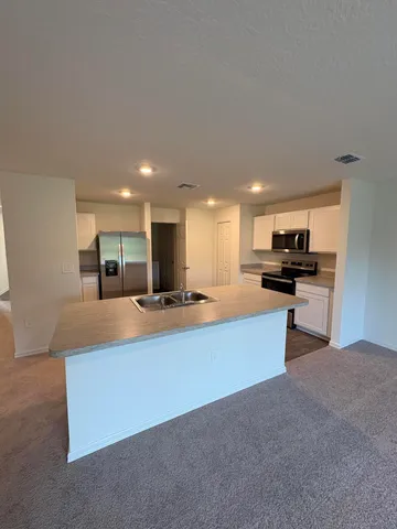 a large kitchen with stainless steel appliances kitchen island a sink dishwasher a stove and a refrigerator with wooden floor