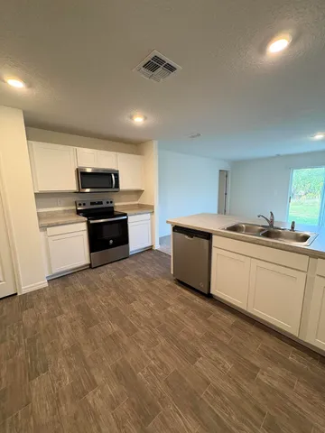 a kitchen with stainless steel appliances a refrigerator sink and white cabinets