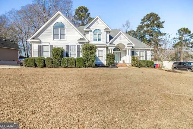 a view of a white house with a yard and large trees