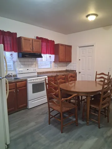 a kitchen with stainless steel appliances granite countertop a table chairs sink and cabinets