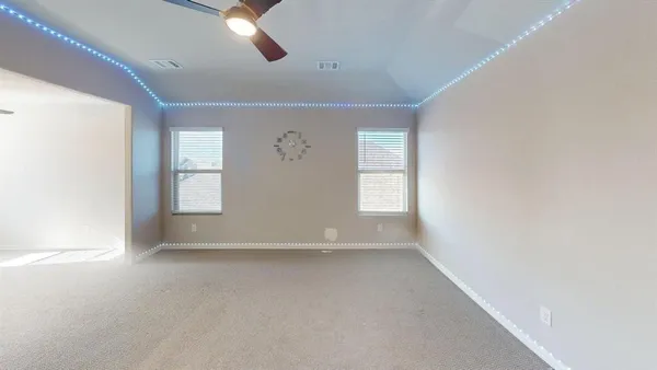 an empty room with windows and chandelier fan