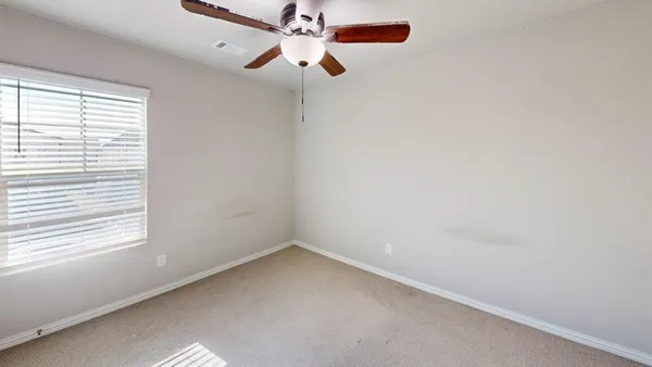 an empty room with a window and a fan