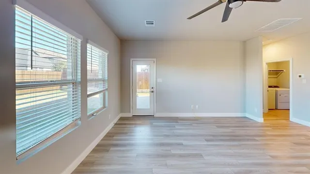 a view of an empty room with glass door and windows