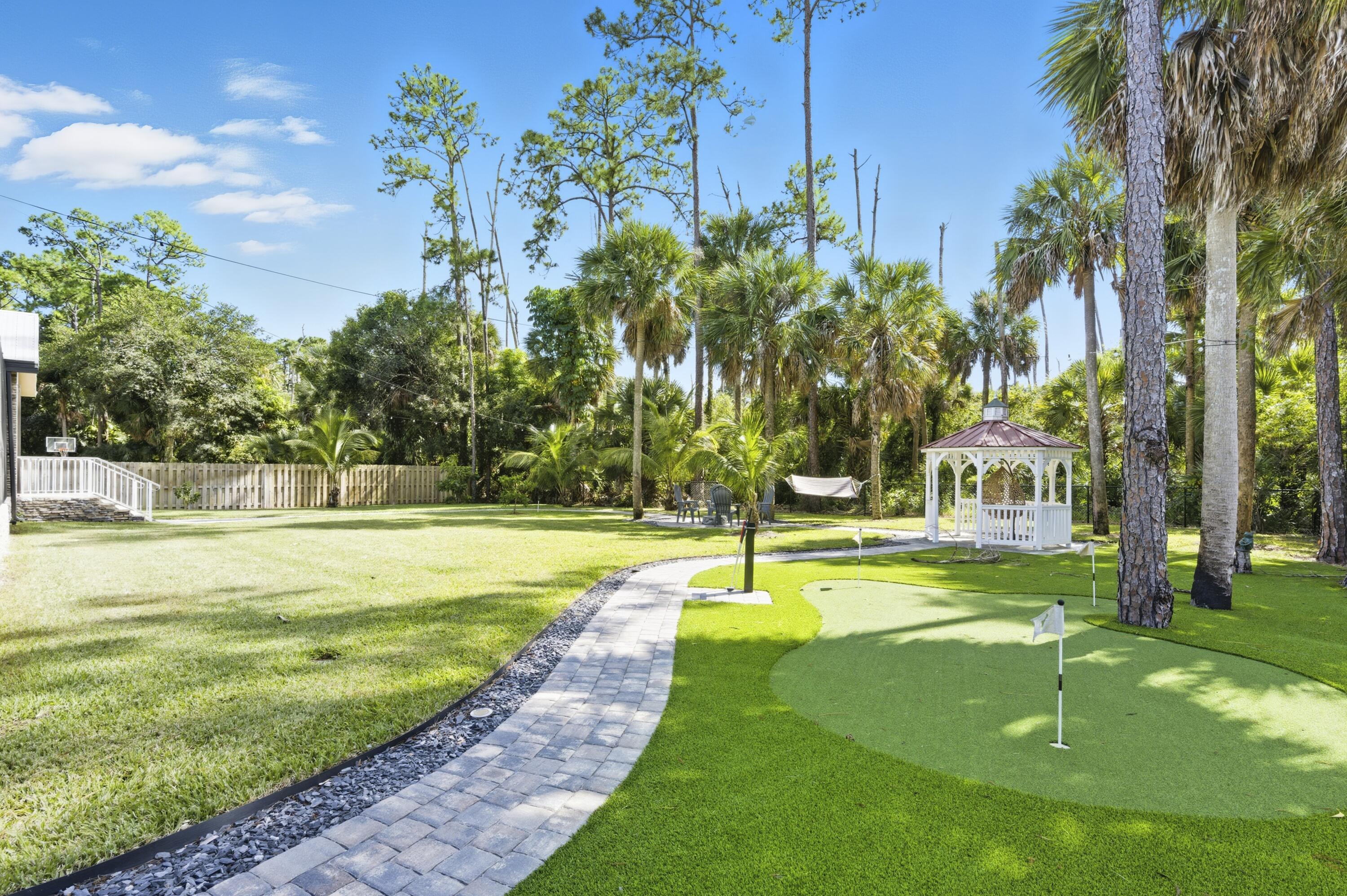 8350 Whispering Oak Way West Palm Beach, FL 33411 - Photo 28 of 51 a view of a swimming pool with a big yard and palm trees