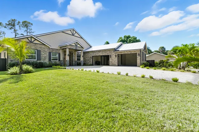 a front view of a house with a big yard and potted plants