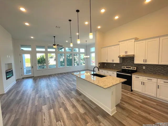 a open kitchen with kitchen island granite countertop wooden floors and wide window