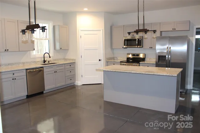 a large kitchen with stainless steel appliances a large counter top a stove a chimney a sink and a refrigerator