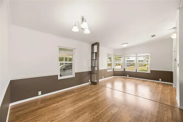 a view of an empty room with window and wooden floor