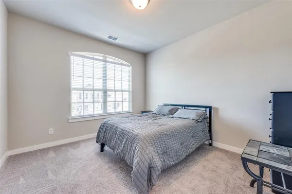 a bed sitting in a spacious bedroom next to a window