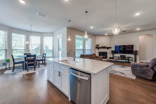 a large kitchen with kitchen island a large island in the center a sink a window cabinets and stainless steel appliances
