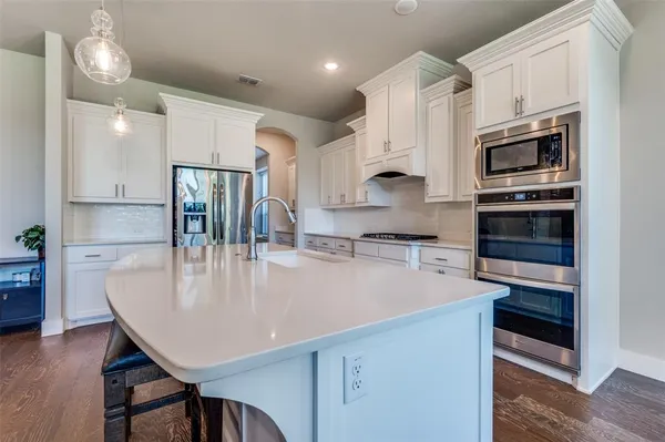 a large kitchen with white cabinets a sink a stove and a refrigerator