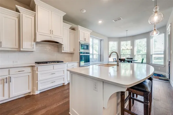 a kitchen with granite countertop a stove a sink and cabinets