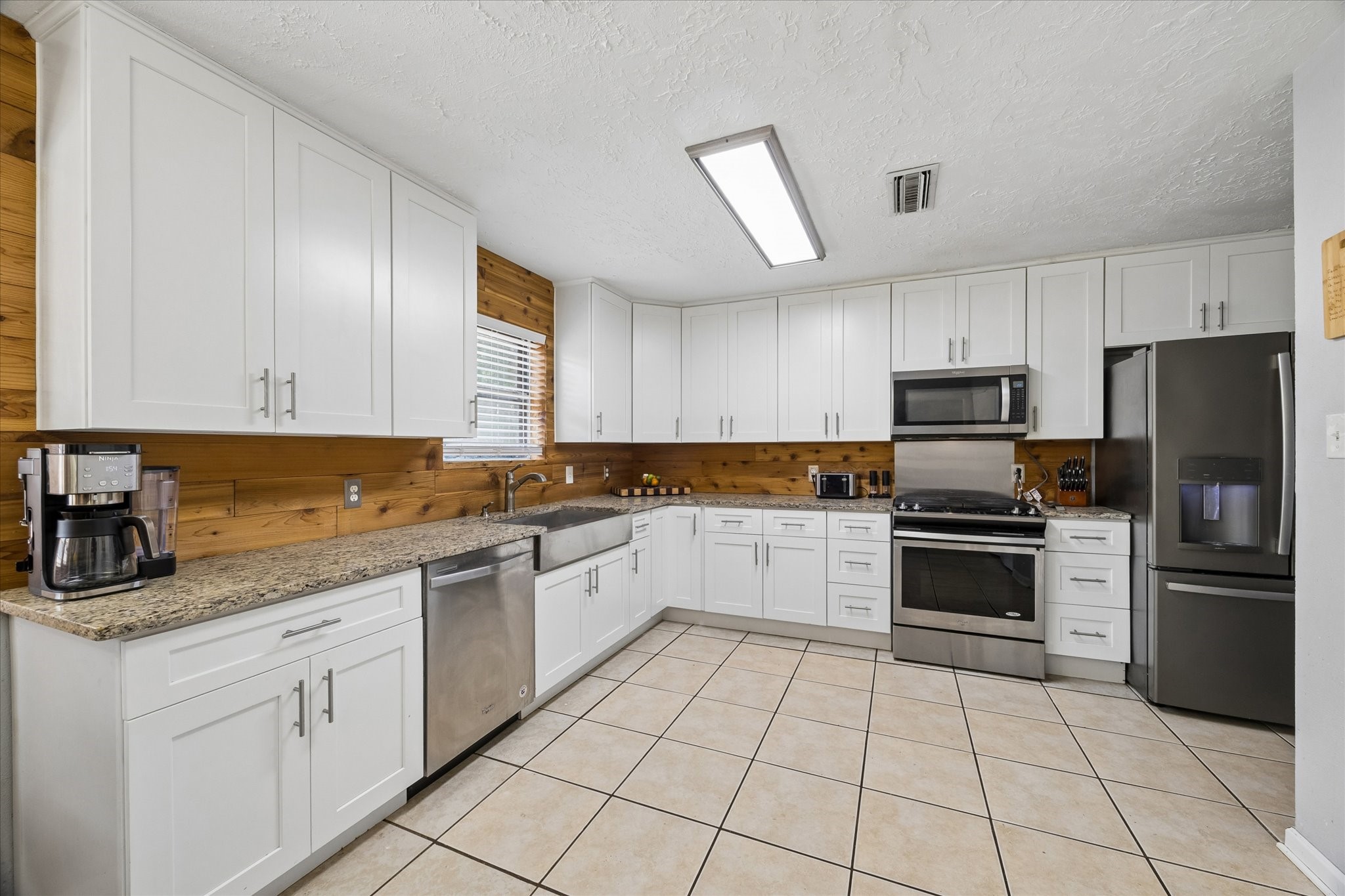 23115 Stepinwolf Lane Spring, TX 77373 - Photo 4 of 18 Kitchen featuring sleek white cabinetry, stainless steel appliances, and warm wood accents, perfect for culinary enthusiasts.