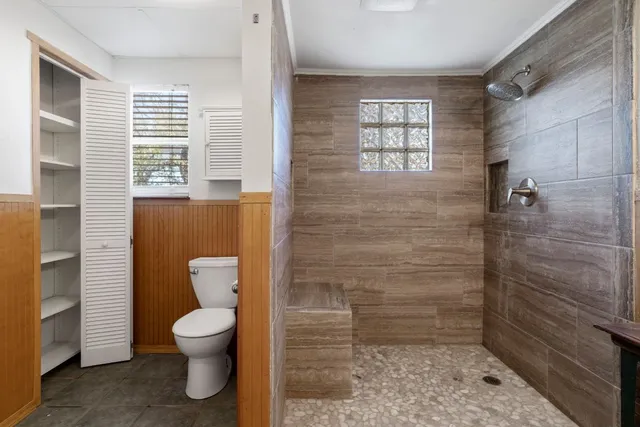 a bathroom with a toilet a window and shower