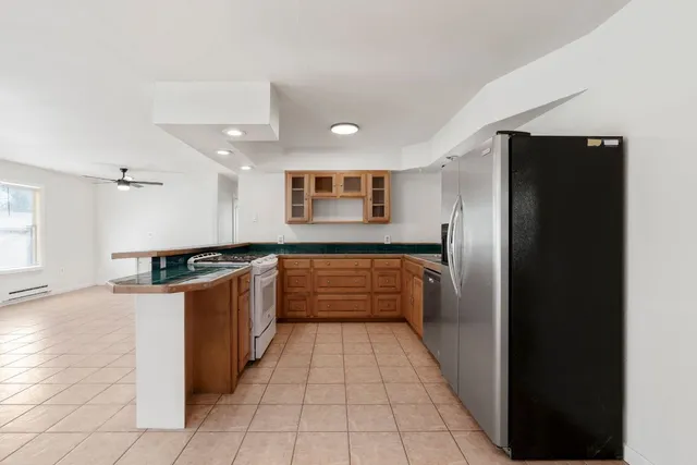 a large kitchen with stainless steel appliances kitchen island granite countertop a refrigerator and a sink