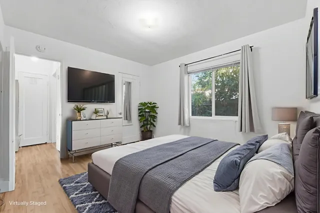 a bedroom with a bed a large window and a flat screen television