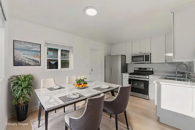 a kitchen with stainless steel appliances kitchen island granite countertop a dining table chairs and refrigerator